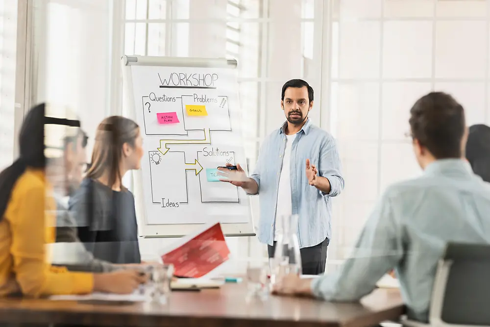 Ein Mann spricht in einem Workshop vor vier Kolleginnen und Kollegen über lösungsorientiertes Denken als Team.