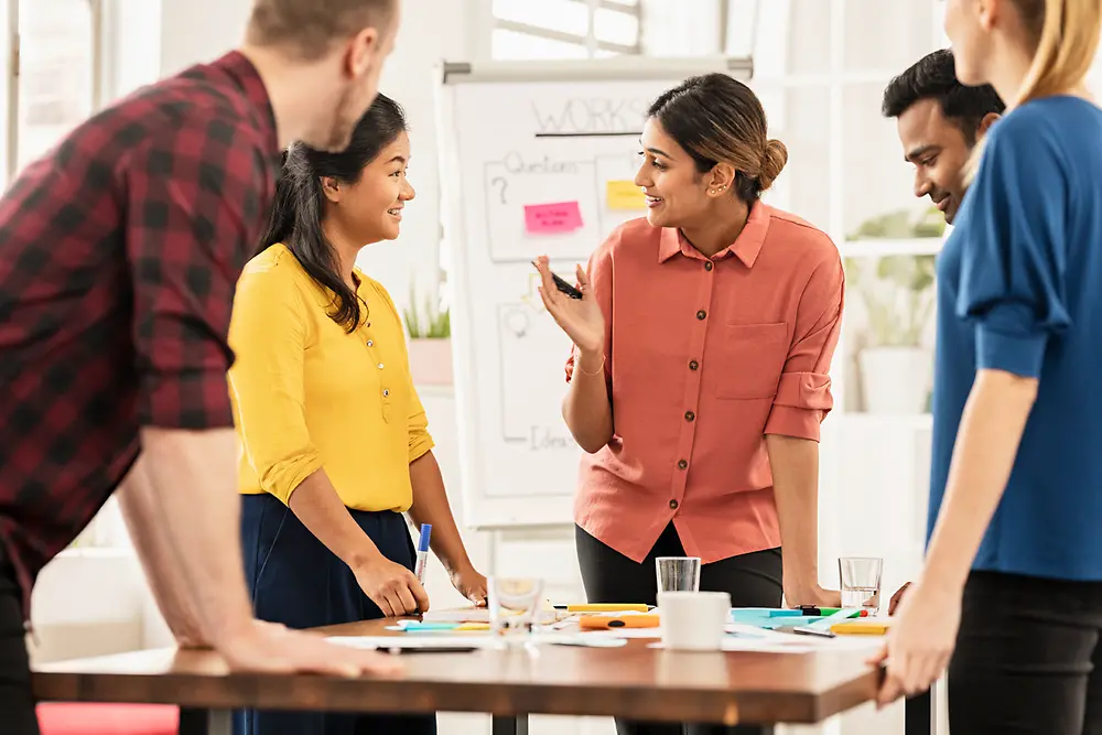 Mitarbeiter:innen beim gemeinsamen Brainstormen vor einer Flipchart. 