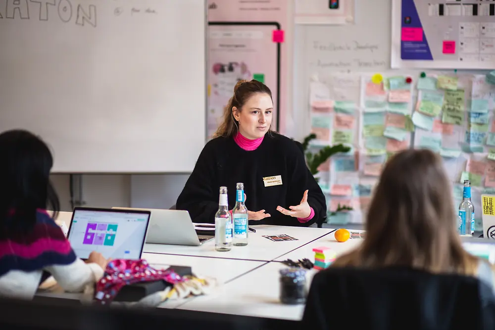 Drei Frauen, die in Workshop-Atmosphäre zusammensitzen und miteinander sprechen.