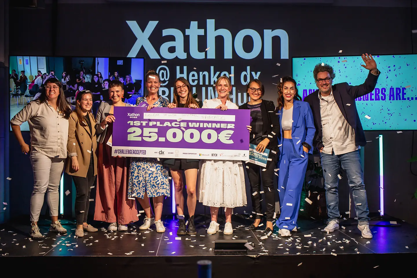 Die Xathon-Gewinner:innen des letzten Jahres stehen gemeinsam mit Vertreter:innen von Henkel dx Ventures auf der Bühne und freuen sich über einen symbolischen Scheck von 25.000 Euro.