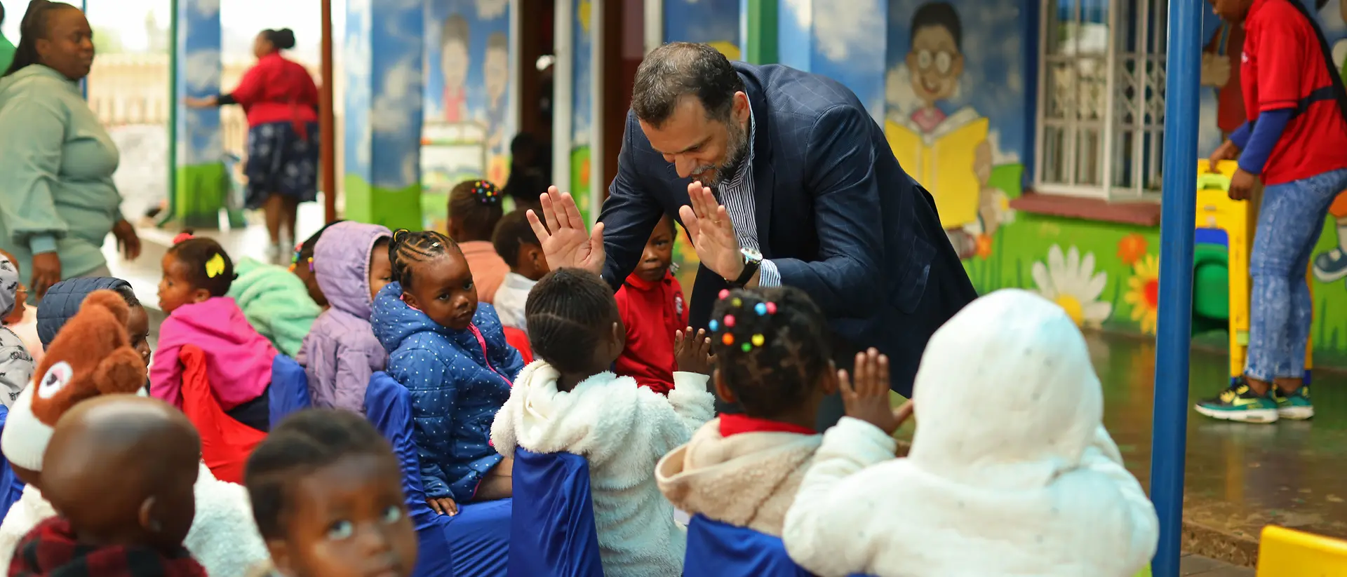 Eine Gruppe von kleinen Kindern klatscht mit einem ehrenamtlichen Helfer ab.