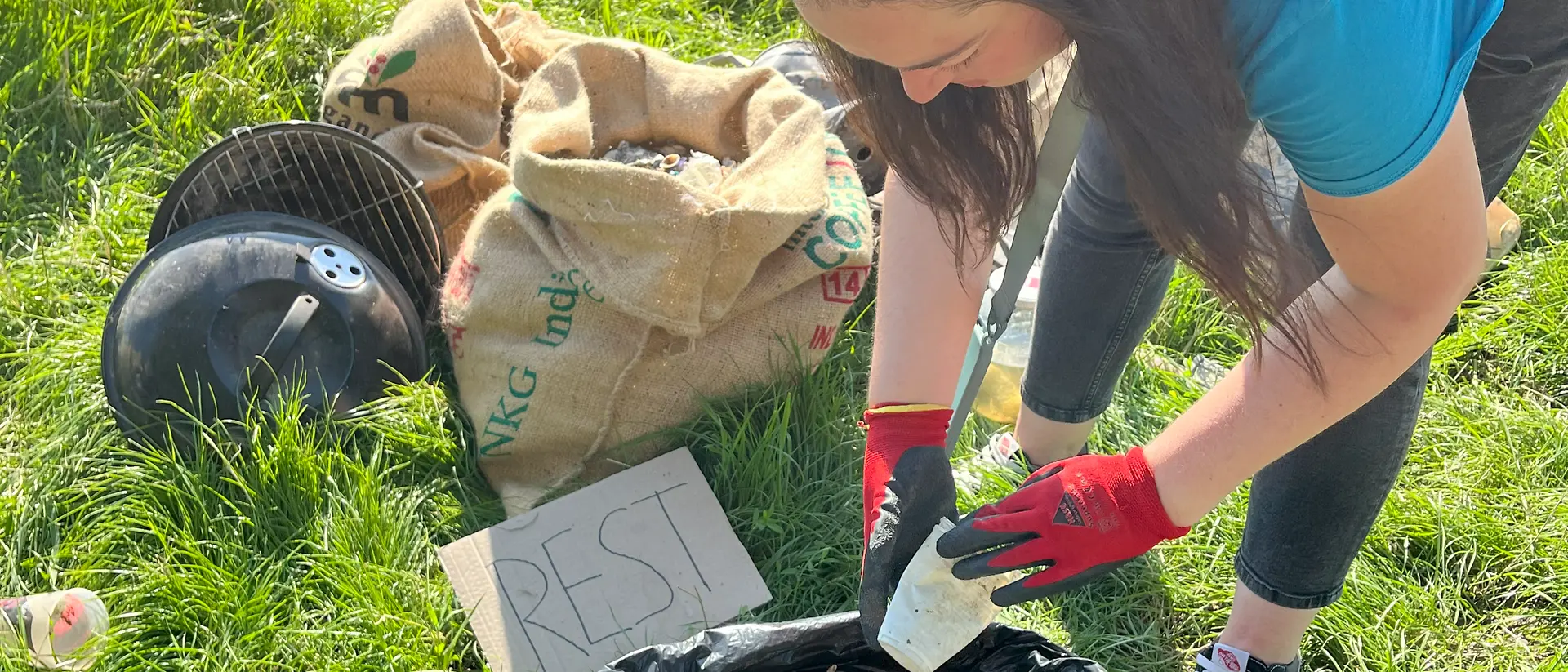 Eine Frau wirft einen Plastikbecher in einen Müllsack.