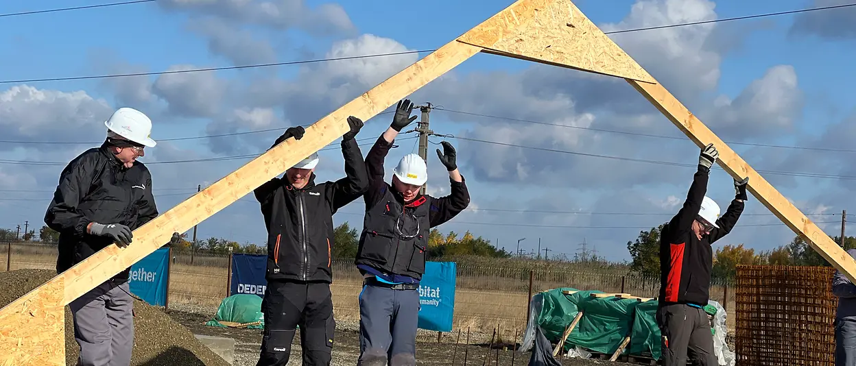 Mehrere Henkel-Mitarbeiter:innen arbeiten zusammen, um das Holzgerüst des Hauses aufzustellen.