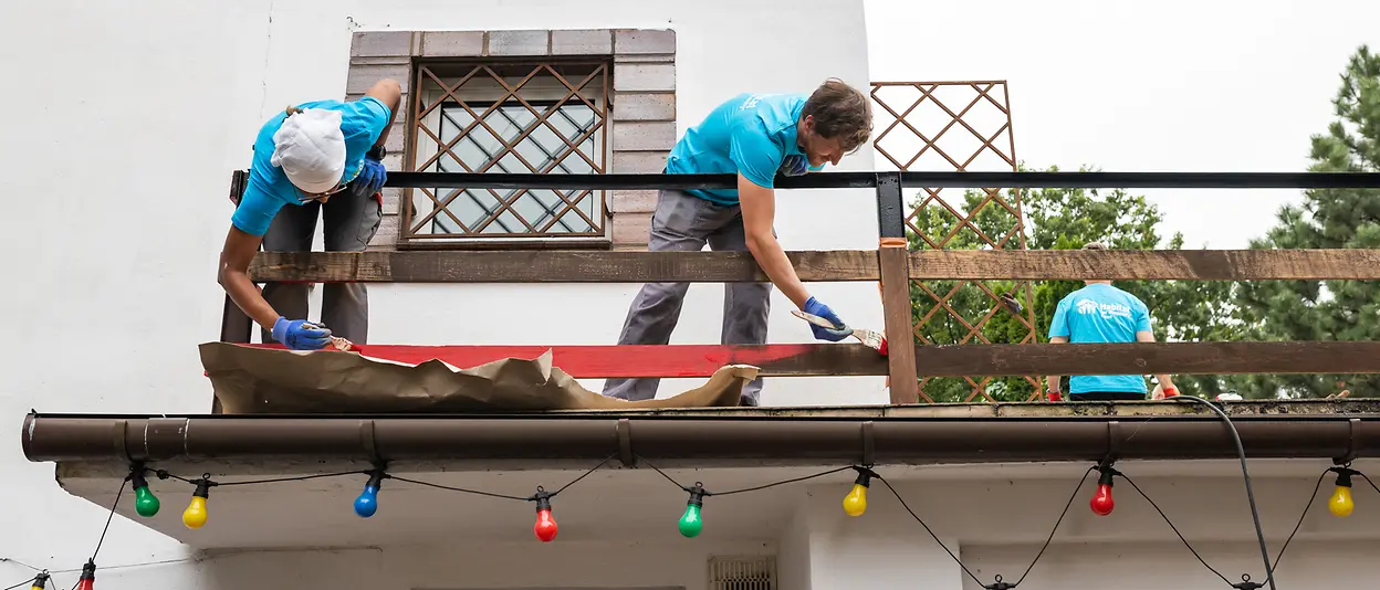 Die Henkel-Freiwilligen bauen und streichen einen Zaun auf dem Balkon des Hauses.