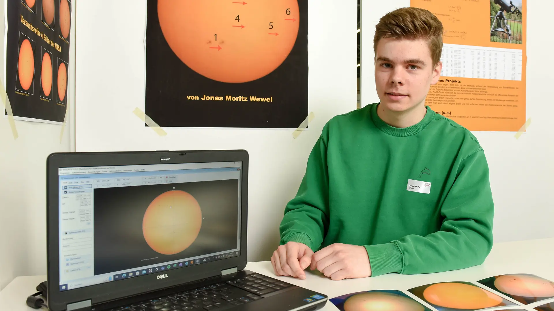 Jonas Moritz Wewel sitzt vor seinem Projektstand und lächelt neben seinem Laptop in die Kamera.