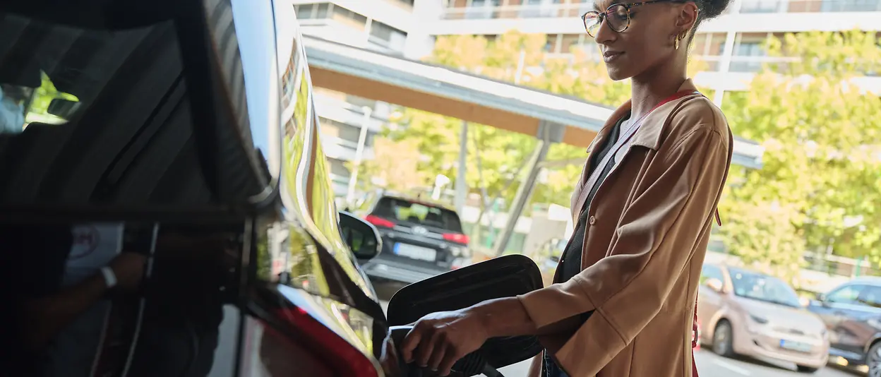 Eine Frau ist gerade dabei ihr E-Auto zu laden.