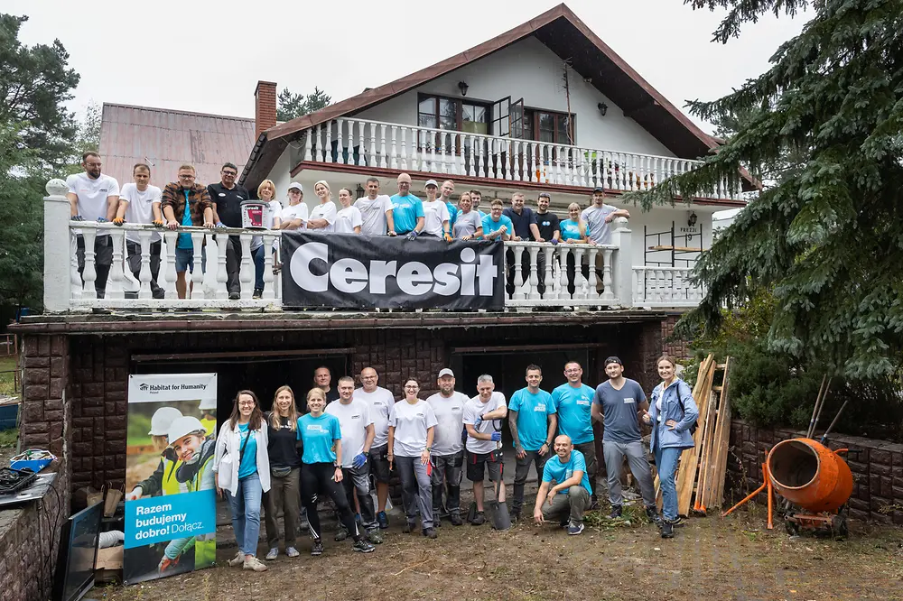 Das Baureise- und polnische Ceresit-Team von Henkel stehen vor dem Haus, das sie gemeinsam renovieren und lächeln in die Kamera. 