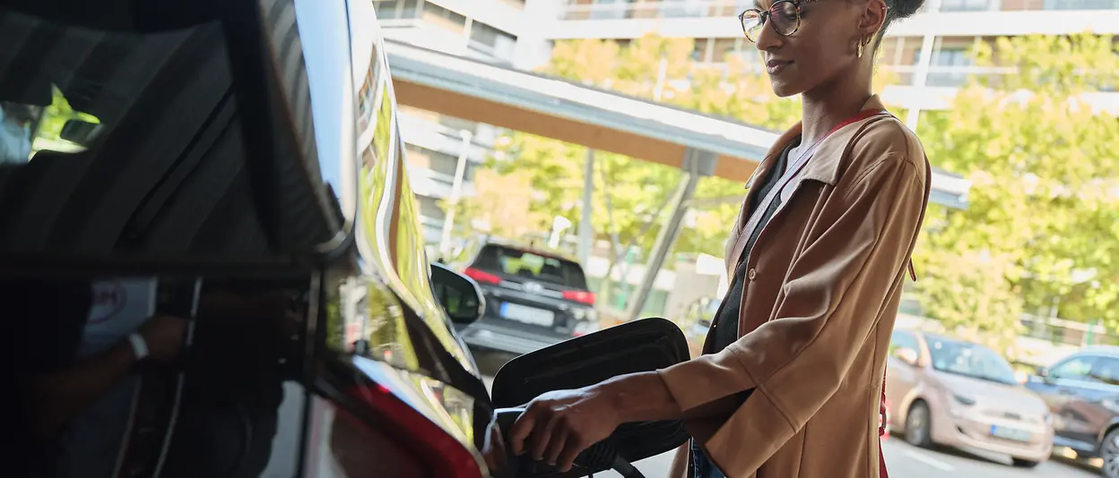 Eine Frau lädt ihr Elektroauto an einer Ladesäule. 