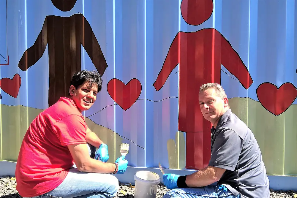 Henkel employees Pradeep Klair and Tom DeFazio paint the illustration 