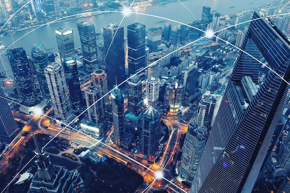 Bird´s eye view of Shangai´s skyscrapers. Several cruved white lines intersect each other above the city, representing connectivity.